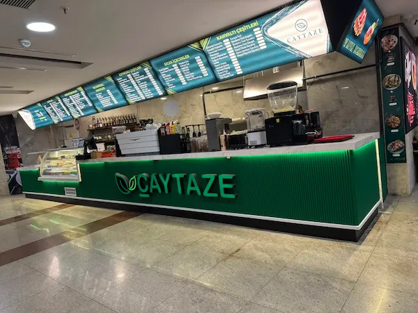 Çaytaze kurumsal konsept, yeşil dikey oluklu panelli, beyaz mermer tablalı ve yeşil LED aydınlatmalı modern cafe kasa bankosu