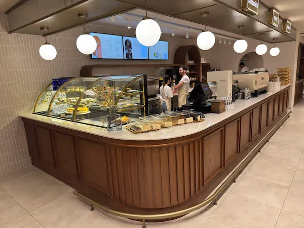 Koyu meşe ahşap çıtalı panellere sahip, kavisli köşe dönüşlü, beyaz mermer tablalı ve bombeli cam pasta vitrinli şık cafe bankosu