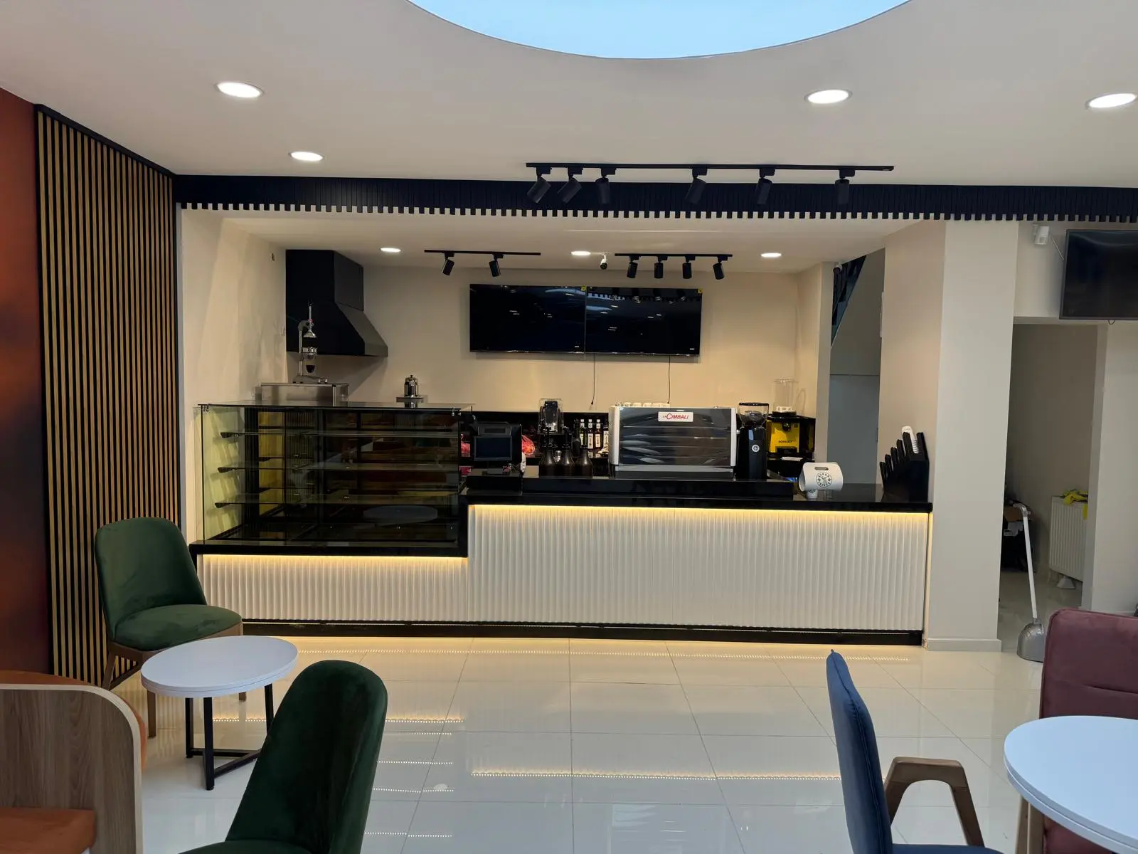 Koyu ahşap oluklu dikey panelli, mermer yan kaplamalı, kavisli bombeli cam vitrinli modern cafe pasta ve tatlı teşhir tezgahı