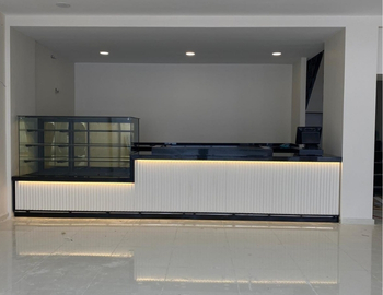 Beyaz dikey oluklu panelli, siyah mermer tablalı, LED aydınlatmalı modern cafe bankosu ve entegre cam pasta teşhir vitrini