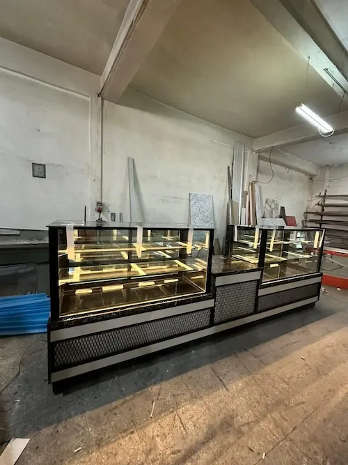 Siyah metal profilli, ön yüzü petek tel (genişletilmiş sac) dekorlu, siyah mermer tablalı, endüstriyel tasarım modern cafe ve pastane teşhir dolabı