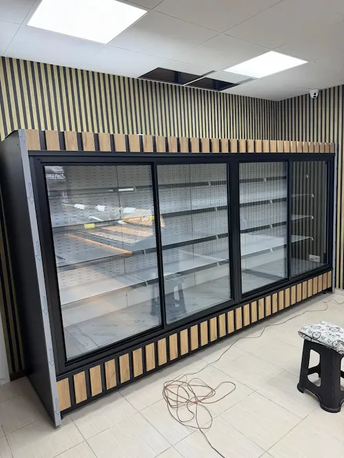 Alt ve üst kısımları ahşap dikey çıta dekorlu, siyah çerçeveli, 4 sürgü cam kapılı, şık ve modern market tipi sütlük dolabı